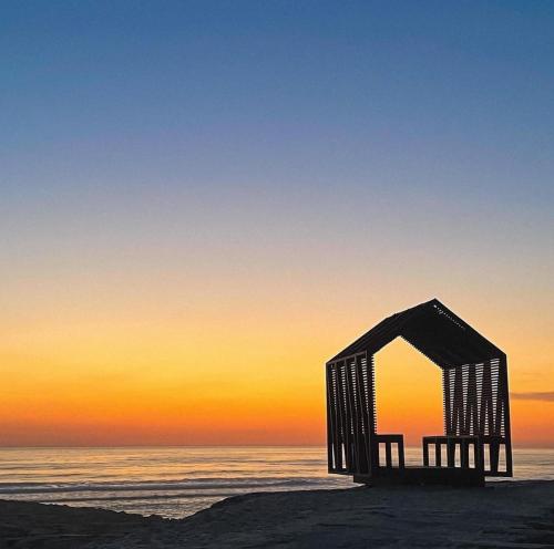 a wooden structure on the beach at sunset at Casa do Mar - Reconnect - T2 com pátio junto à praia in Ovar