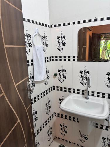 a bathroom with black and white tiled walls and a sink at Mar de Moreré in Cairu