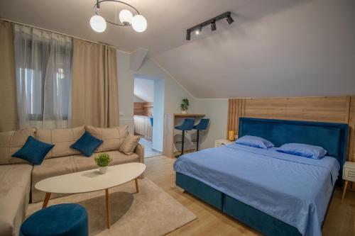 a bedroom with a blue bed and a couch at Ramonda Riverside in Veliko Gradište