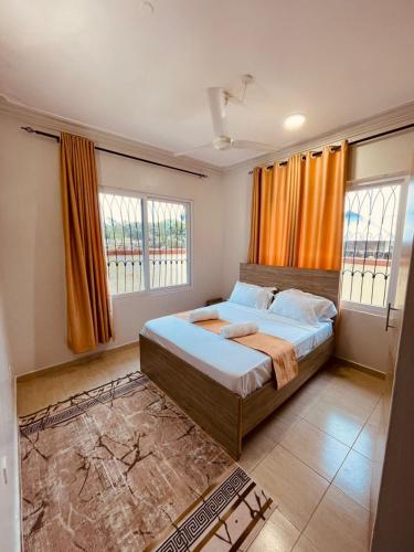 a bedroom with a large bed with orange curtains at SeyniKe 2BR Apartment - Nyali - AC, WiFi - Parking in Mombasa