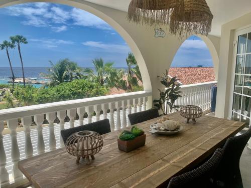 a table on a balcony with a view of the ocean at Appartement Flamboyan op Ocean Resort, Mambo Curaçao in Willemstad