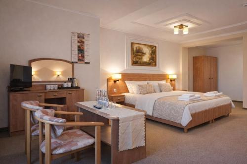 a hotel room with a bed and a table and chair at Piastun SPA&Wellness Krynica-Zdrój in Krynica Zdrój