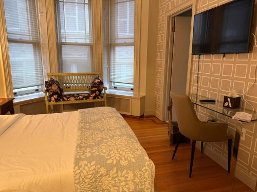 a bedroom with a bed and a desk and windows at Washington Park Inn in Albany