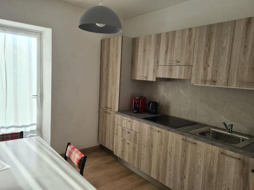 a kitchen with wooden cabinets and a sink and a table at Appartamenti Croz del Re 2 in Andalo