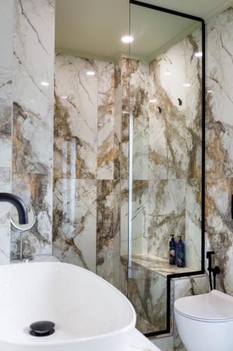 a bathroom with a tub and a glass shower at Angels Riva Boutique Residences in Kastoria
