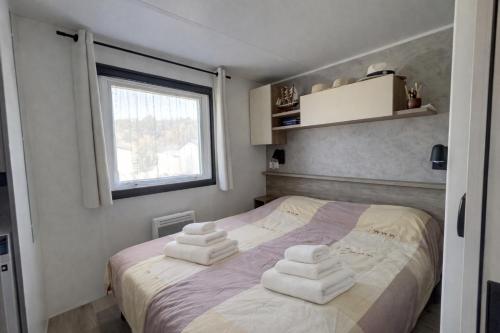 a bedroom with a bed with towels on it at Mobilhome La Pause Océane - La Plage in Mimizan-Plage