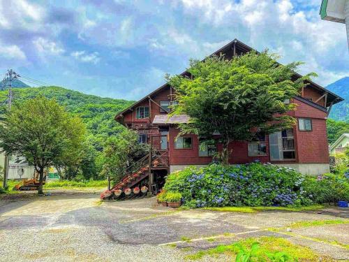 a large red house with a tree in front of it at Heidi Guest House in Yuzawa