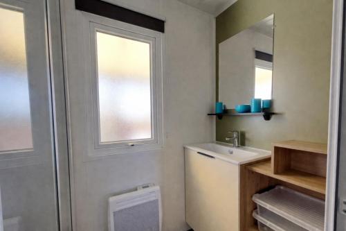a bathroom with a sink and a toilet and a window at Mobilhome La Pause Océane - La Plage in Mimizan-Plage
