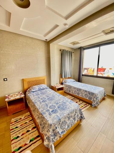 a room with two beds and a large window at Genova surf house in Imsouane