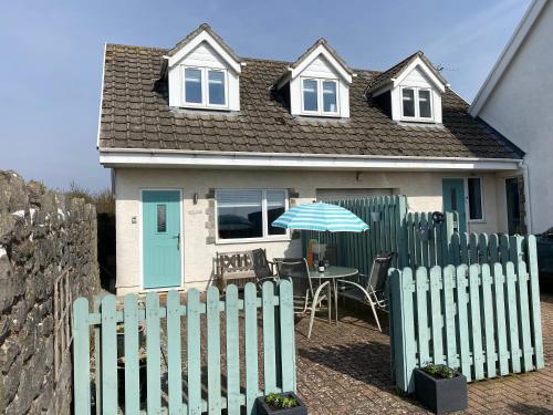 a house with a green fence and a table with an umbrella at Sea dream lodge -coastal location/sea views/self-contained in Southerndown