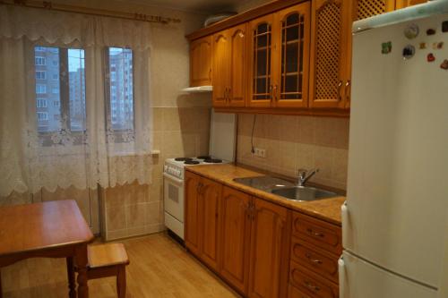 a kitchen with wooden cabinets and a white refrigerator at Dauman Apartment in Narva
