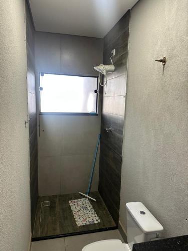 a bathroom with a shower with a toilet and a window at Moderna área com Wi-Fi e ar condicionado in Americana