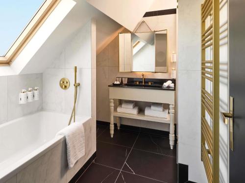 a bathroom with a sink and a tub and a mirror at l'Echiquier Opéra Hotel Paris - MGallery Collection in Paris
