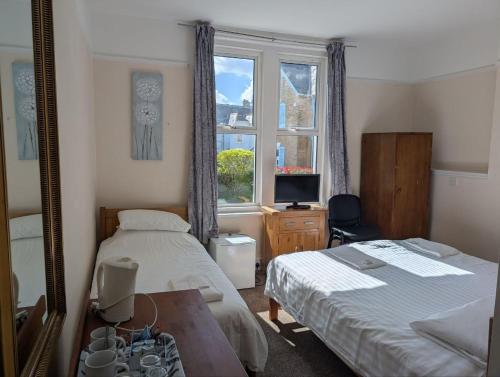 ein Schlafzimmer mit zwei Betten und einem Fenster in der Unterkunft Dolphins Hotel in Bournemouth