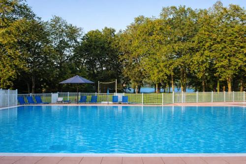 a large swimming pool with blue chairs and a fence at Maison cosy 6 pers - piscine chauffée - nature et lac - Monflanquin in Monflanquin