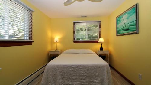 a small bedroom with a bed and two windows at Cottage On Cambridge in Cape May Point