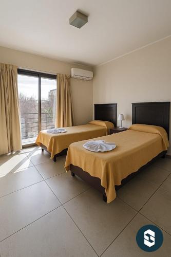 a hotel room with two beds and a window at Central Suites Hotel in Villa Carlos Paz