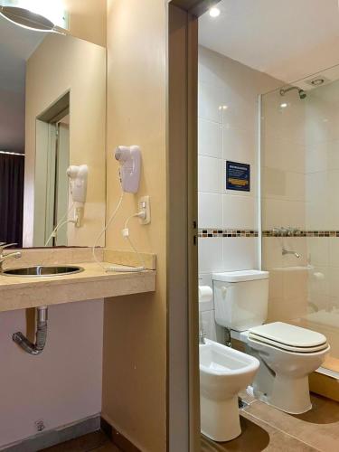a bathroom with a toilet and a sink and a mirror at Central Suites Hotel in Villa Carlos Paz