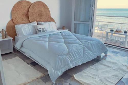 a bedroom with a large bed with a view of the ocean at Lappartement Pied dans leau in Douar el Hafey