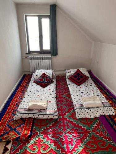 two beds in a room with a rug on the floor at Taldy-Suu Guesthouse in Taldysu