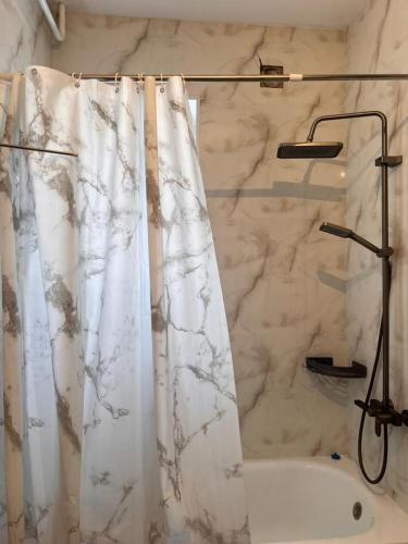 a bathroom with a marble shower curtain and a tub at Taldy-Suu Guesthouse in Taldysu