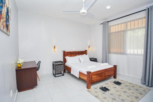 a bedroom with a bed and a desk and a window at Diani Dream stays in Diani Beach