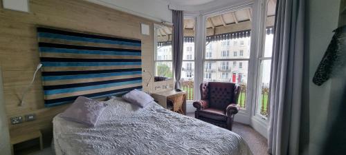 a bedroom with a bed and a chair and a window at Marine View in Brighton & Hove