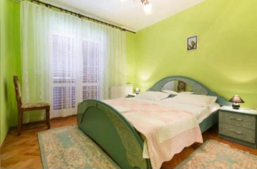 a green bedroom with a large bed and a window at Primošten-Huljev in Primošten