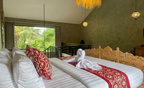 a bedroom with a large bed with red and white pillows at Juminten Villa in Ubud