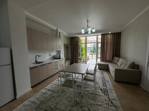 a kitchen and living room with a table and a couch at Royal Beach Cottage Issyk Kul in Chok-Tal