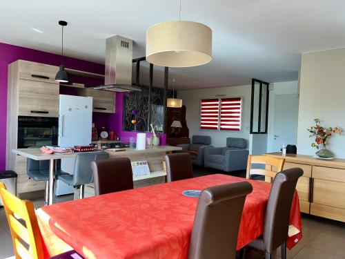 a kitchen and dining room with a red table and chairs at Le Relais du 49 - Gîte in La Séguinière