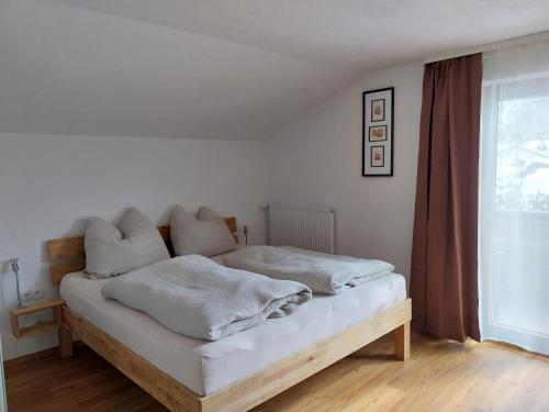 a bedroom with a bed with white sheets and a window at Haus Lorang in Pfronten