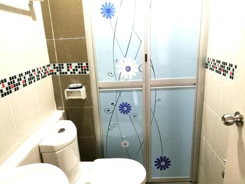 a bathroom with a toilet and flowers on the shower door at NF Suites D'Perdana Condo in Kota Bharu