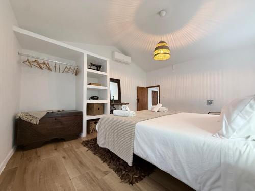 a white bedroom with a large bed and a shelf at Casa do Serro de Lá in Santa Clara-a-Nova