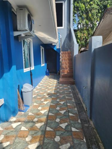 a blue building with a stone walkway next to a house at Xavier Heights Gate 1 Pad in Cagayan de Oro