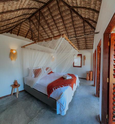 a bedroom with a bed with a mosquito net at Vila Ronquinha - Arpoador in Tutóia
