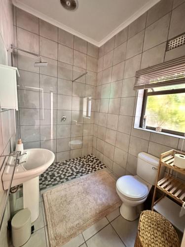a bathroom with a shower and a toilet and a sink at 95 on Acacia in Helderberg