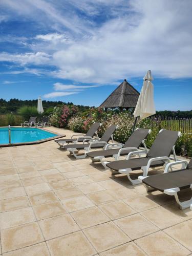 a row of chaise lounge chairs next to a pool at Les Cabanes de Rouffignac in Rouffignac Saint-Cernin