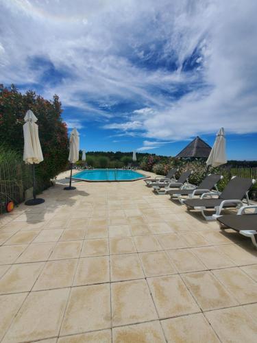 a swimming pool with lounge chairs and umbrellas at Les Cabanes de Rouffignac in Rouffignac Saint-Cernin