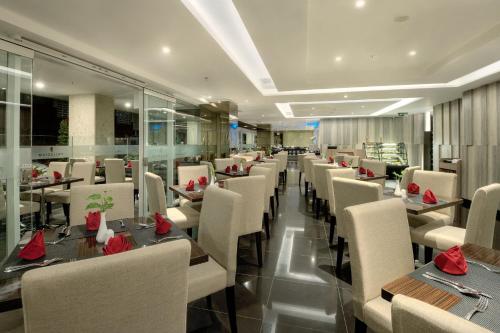 a restaurant with tables and chairs with red flowers on them at Platinum Adisucipto Hotel & Conference Center in Yogyakarta