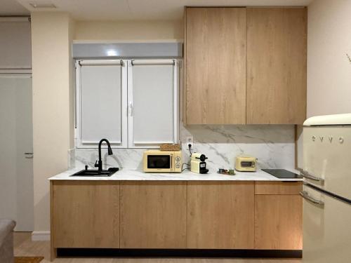 a kitchen with wooden cabinets and a sink and a refrigerator at Bianca Suites II in Bormujos