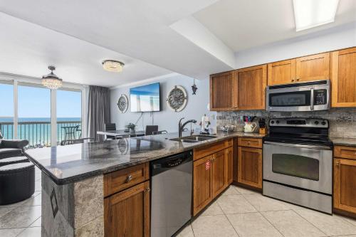 a kitchen with wooden cabinets and stainless steel appliances at Pelican Beach Resort 504 in Destin