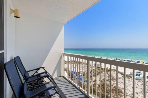 a balcony with two chairs and the beach at Pelican Beach Resort 504 in Destin