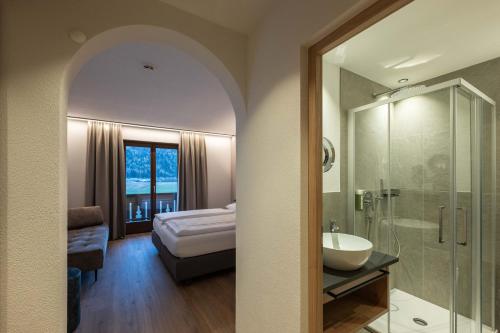 a bathroom with a sink and a shower and a bed at Hotel Mirabell in Campo Tures