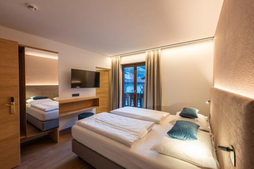 a hotel room with two beds and a television at Hotel Mirabell in Campo Tures