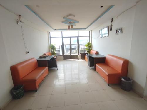 an empty waiting room with orange chairs and tables at Hotel Crown Palace in Dunga Gali