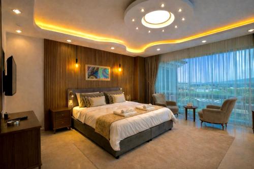 a bedroom with a large bed and a large window at Villa Nuri Konaklama in Çiftlik