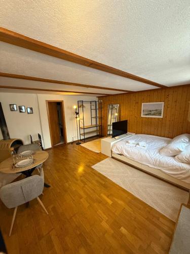 ein großes Schlafzimmer mit einem Bett, einem Tisch und einem Esstisch in der Unterkunft Studio Idylle in Ringgenberg