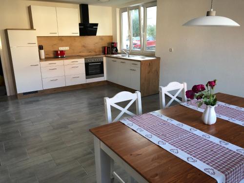 a kitchen with a wooden table and a kitchen with white cabinets at Gästehaus AlbTraum in Reutti