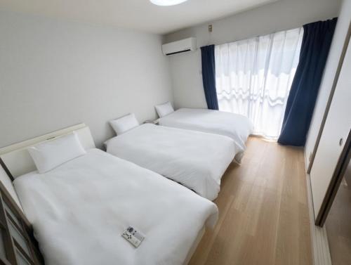 two beds in a room with a window at ITO-STAY Apartment Hotel 阿蘇くまもと空港 #201 in Ozu